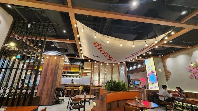 ChilChil interior — festoon bulbs strung under a canvas awning above wooden tables